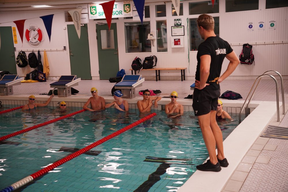 Oskar arbetar med simmare vid bassängkanten